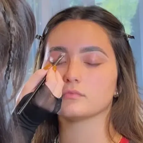 A client receiving having her eyeshadow applied by a High Brow Social Club team member
