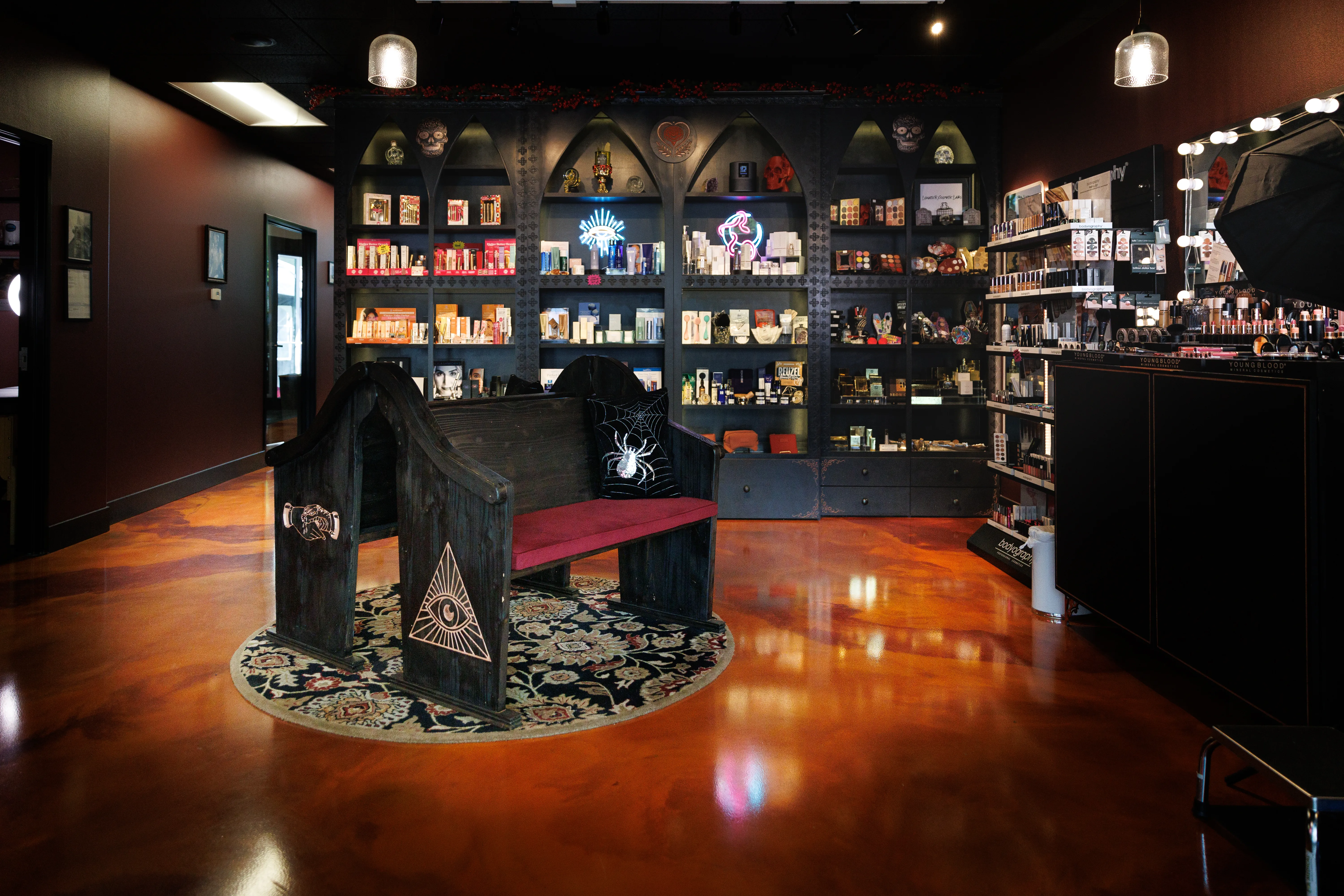 High end, gothic-style salon interior with dark arched shelving and apothecary benches for waiting
